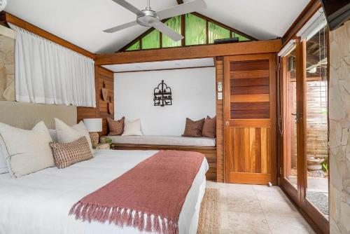 a bedroom with a large bed with a ceiling fan at Byron Blisshouse - multi-home retreat with pool in Byron Bay