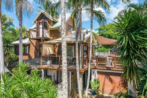 a house with palm trees in front of it at Byron Blisshouse - multi-home retreat with pool in Byron Bay
