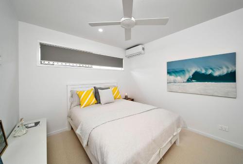 a white bedroom with a bed and a ceiling fan at A Perfect Stay - Byron Sunrise in Byron Bay
