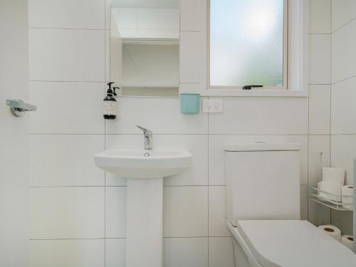 uma casa de banho branca com um lavatório e um WC em The Blockhouse - Whangamatā Holiday Home em Whangamata