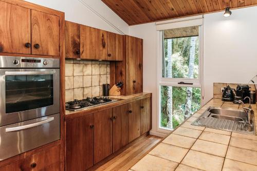 a kitchen with wooden cabinets and a stove top oven at Cape Breeze - 5 BR home with headland views in Byron Bay