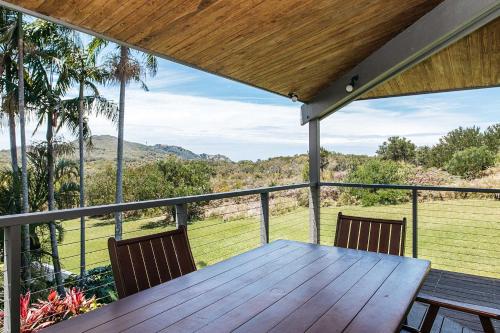 a wooden table and chairs on a balcony with a view at Cape Breeze - 5 BR home with headland views in Byron Bay