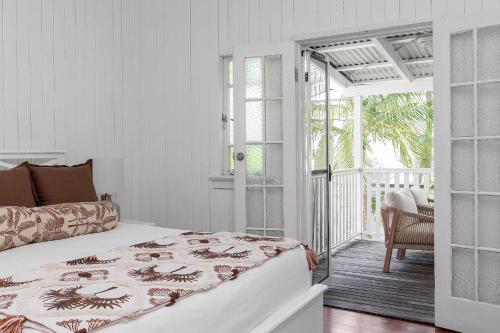 a white bedroom with a bed and a balcony at Cape Cottage - 5 bed charming cottage close to everything in Byron Bay