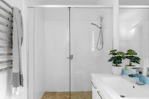 a bathroom with a glass shower and a sink at Cape Cottage - 5 bed charming cottage close to everything in Byron Bay