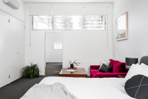 a bedroom with a bed and a red couch at A Perfect Stay - Clique 2 in Byron Bay
