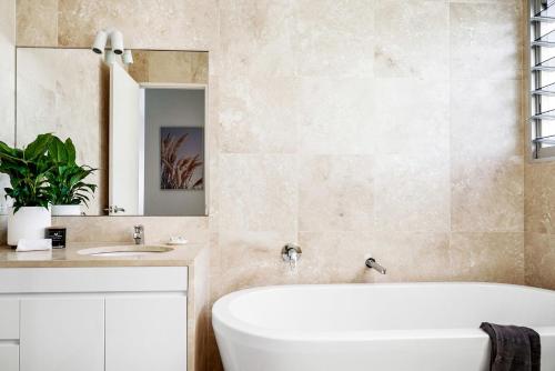 a bathroom with a tub and a sink and a mirror at A Perfect Stay - Clique 2 in Byron Bay