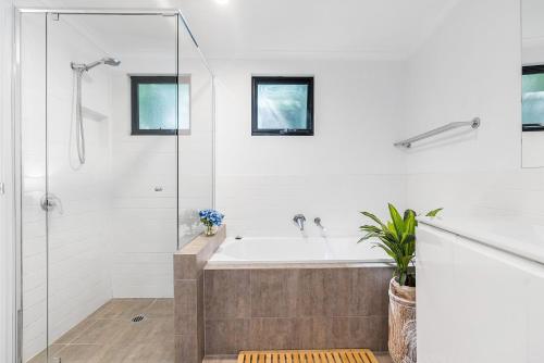 a white bathroom with a tub and a shower at A Perfect Stay - Gidgets House and Studio in Byron Bay