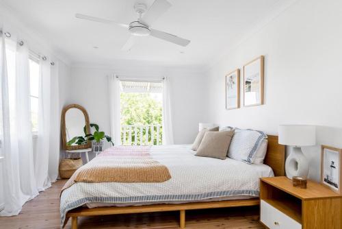 a white bedroom with a bed and a window at A Perfect Stay - Hummingbird in Byron Bay