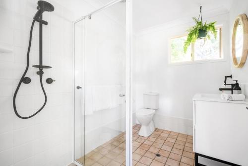 a white bathroom with a shower and a toilet at A Perfect Stay - Hummingbird in Byron Bay