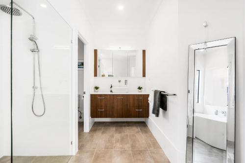 a bathroom with a shower and a sink and a mirror at A Perfect Stay - Julian Rocks House in Byron Bay