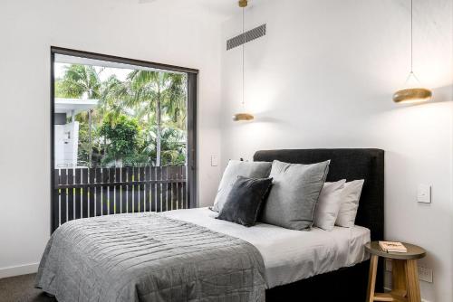 een slaapkamer met een bed en een groot raam bij A Perfect Stay - KoKos Beach House 2 in Byron Bay