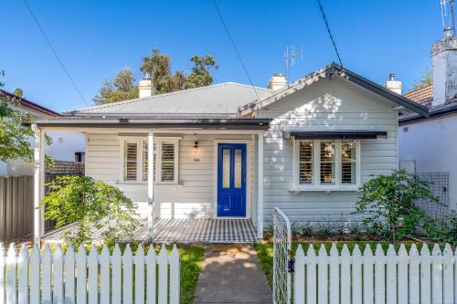 a white house with a blue door at Johnno's Cottage - Prime Location - Sleeps 4 in Orange