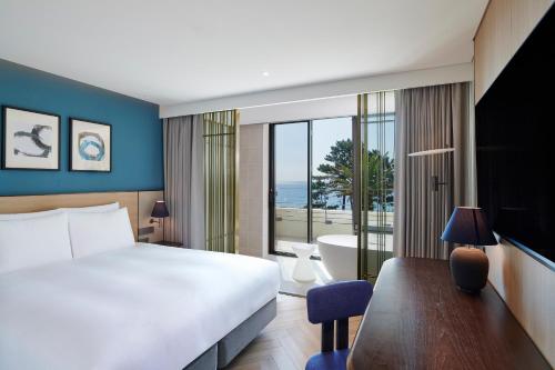 a bedroom with a bed and a view of the ocean at Parnas Hotel Jeju in Seogwipo