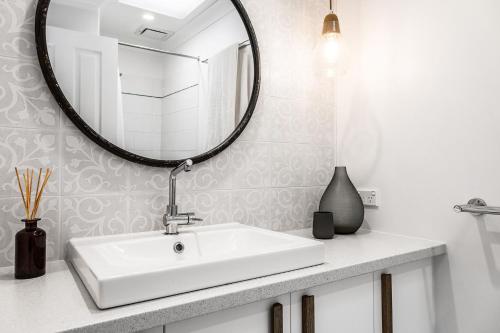 uma casa de banho com um lavatório branco e um espelho. em A Perfect Stay - Little Geckos em Byron Bay