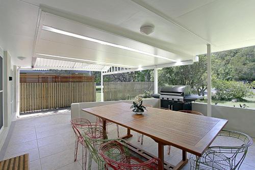a patio with a wooden table and chairs and a grill at Mi Casa - stylish beach house near town & surf in Byron Bay