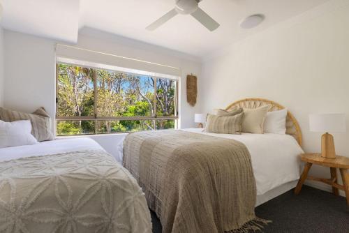 two beds in a bedroom with a window at Oceanfront Byron Palms - 2 BR Main Beach apartment in Byron Bay