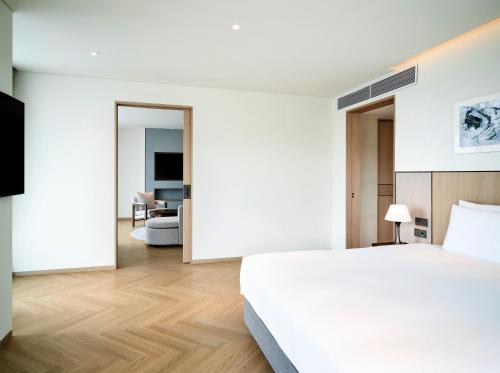 a bedroom with a white bed and a living room at Parnas Hotel Jeju in Seogwipo