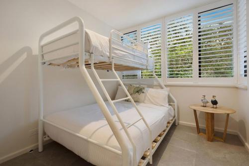 a bedroom with two bunk beds and a table at A Perfect Stay - Pacific Blue in Byron Bay