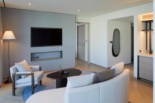 a living room with a couch and chairs and a tv at Parnas Hotel Jeju in Seogwipo