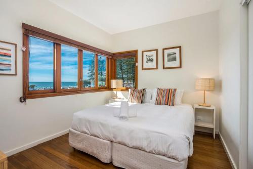 een slaapkamer met een groot wit bed en een raam bij A Perfect Stay - Quiksilver Apartments The Pass in Byron Bay