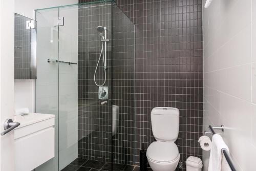 a bathroom with a toilet and a glass shower at A Perfect Stay - Quiksilver Apartments The Pass in Byron Bay