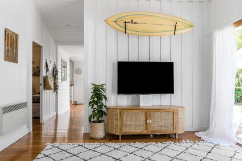 a living room with a flat screen tv on a wall at San Juan Surfers Cottage - prime Byron location in Byron Bay