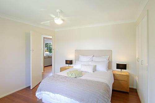 1 dormitorio blanco con 1 cama y 2 lámparas en A Perfect Stay - Su Casa, en Byron Bay