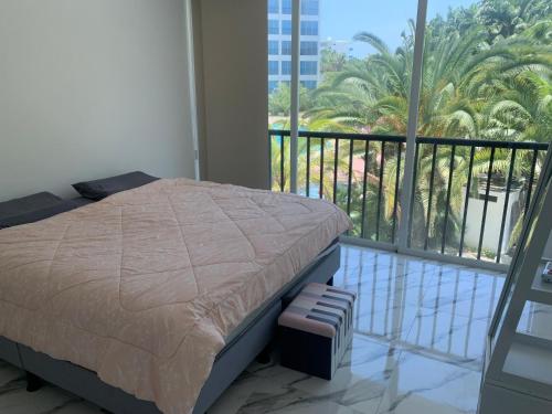 um quarto com uma cama e uma varanda com palmeiras em Punta Centinela ( Cancún chiquito) em Punta Blanca