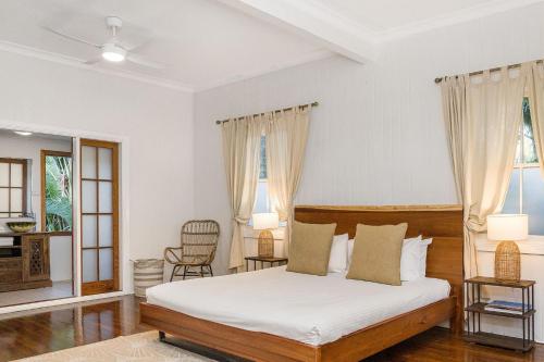 a bedroom with a bed with white sheets and curtains at Skye Lodge - 7 Bedroom charming Balinese retreat with designer pool in Byron Bay