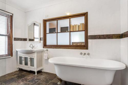 a white bathroom with a tub and a sink at Skye Lodge - 7 Bedroom charming Balinese retreat with designer pool in Byron Bay