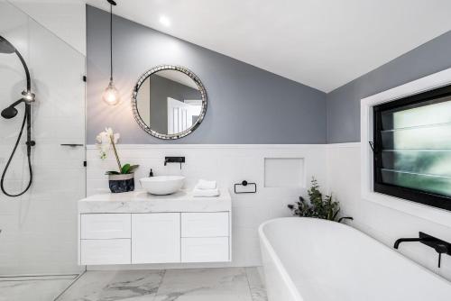 a bathroom with a tub and a sink and a mirror at A Perfect Stay - Solstice in Byron Bay