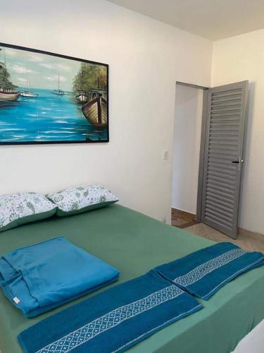 a bedroom with a green bed with a picture on the wall at Pousada Luciana Dias in Palmas
