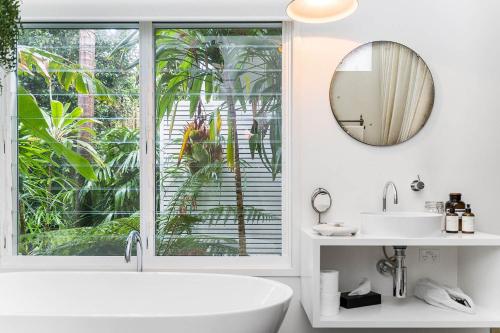 baño con bañera, lavabo y ventana en A Perfect Stay - The Chalet, en Byron Bay