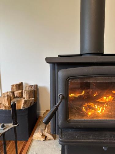 a stove with a pile of logs in a room at Two Twenty Two Farm Stay in Grassy