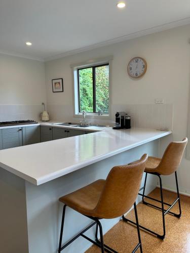 a kitchen with a large white counter and two chairs at Two Twenty Two Farm Stay in Grassy