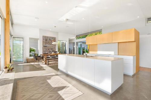 a kitchen with white cabinets and a dining room at The Springs - architect-designed home with pool in Mullumbimby