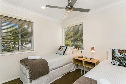a white bedroom with two beds and a window at A Perfect Stay - Tradewinds 4 in Bangalow