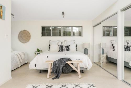 een witte slaapkamer met een bed en een spiegel bij A Perfect Stay - The White Rabbit in Byron Bay