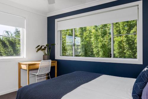 a bedroom with a bed and a desk with a window at A Perfect Stay - Villa St Helena in Byron Bay