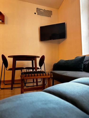 a living room with a couch and a table and a tv at MRTN APARTMENTS Studio & Suites - Aix-les-Bains, hypercentre in Aix-les-Bains