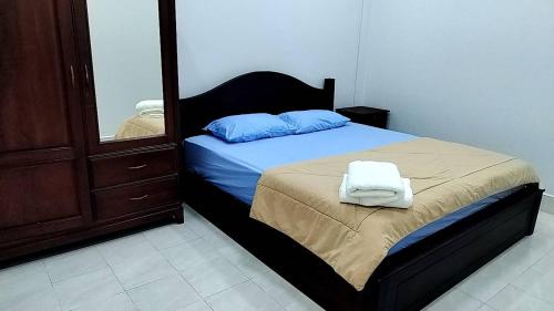 a bedroom with a bed with blue pillows and a mirror at CS Apartment in Vientiane