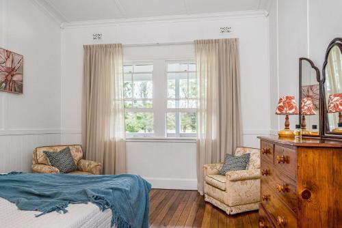 1 dormitorio con 1 cama, 2 sillas y ventana en A Perfect Stay - Mullum River House, en Mullumbimby