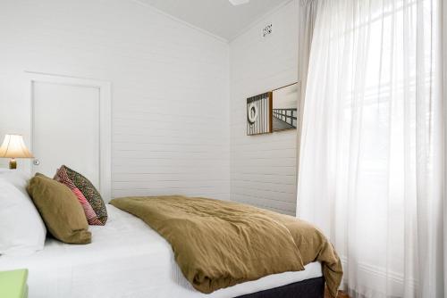 a white bedroom with a bed and a window at Mullum River House - waterfront heritage home in Mullumbimby