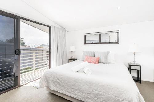 a white bedroom with a bed and a large window at A Perfect Stay - Sandy Feet in Lennox Head