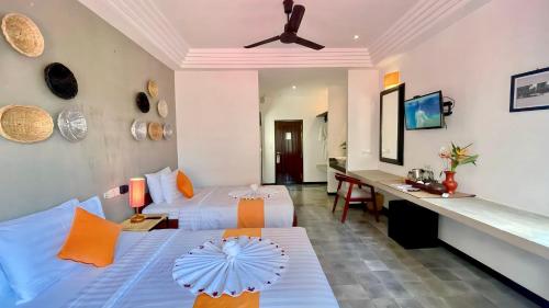 a bedroom with two beds and a desk with an umbrella at Boutique Indochine d'Angkor in Siem Reap