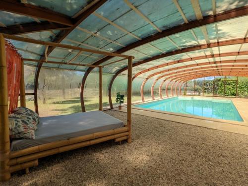 une pergola avec un lit et une piscine dans l'établissement Gîte familial avec piscine chauffée, jardin privé et équipements bébé en Charente - FR-1-653-182, à Montmoreau