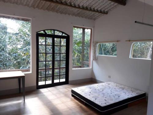 1 dormitorio con 1 cama en una habitación con ventanas en Tranquilidade e conforto na floresta - Rota do Vinho en São Roque