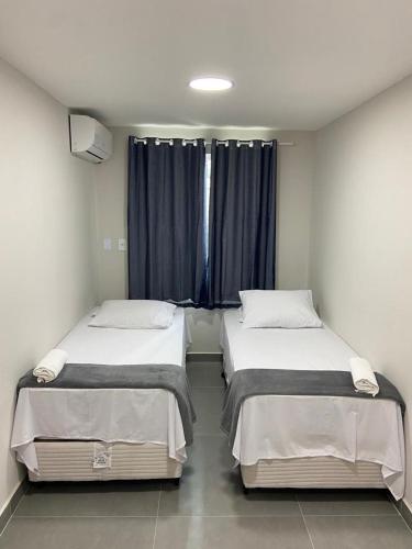 two beds in a small room with a window at Brisa dos Anjos Suítes in Arraial do Cabo