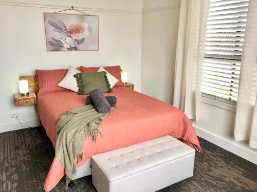 a bedroom with a red bed and a window at The Corner Cottage Orbost in Orbost