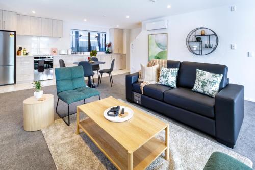 a living room with a black couch and a table at CBD Gem: Walk to everything, 3 bedroom 2 bath in Christchurch